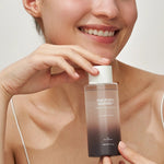 A model holding a bottle of Haruharu Wonder Black Rice Hyaluronic Toner, showcasing its sleek design and gradient packaging.