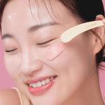A model applying 'I'm From Beet Purifying Mask' on her cheek with its wooden spatula, showcasing its creamy and rich texture for purifying the skin.