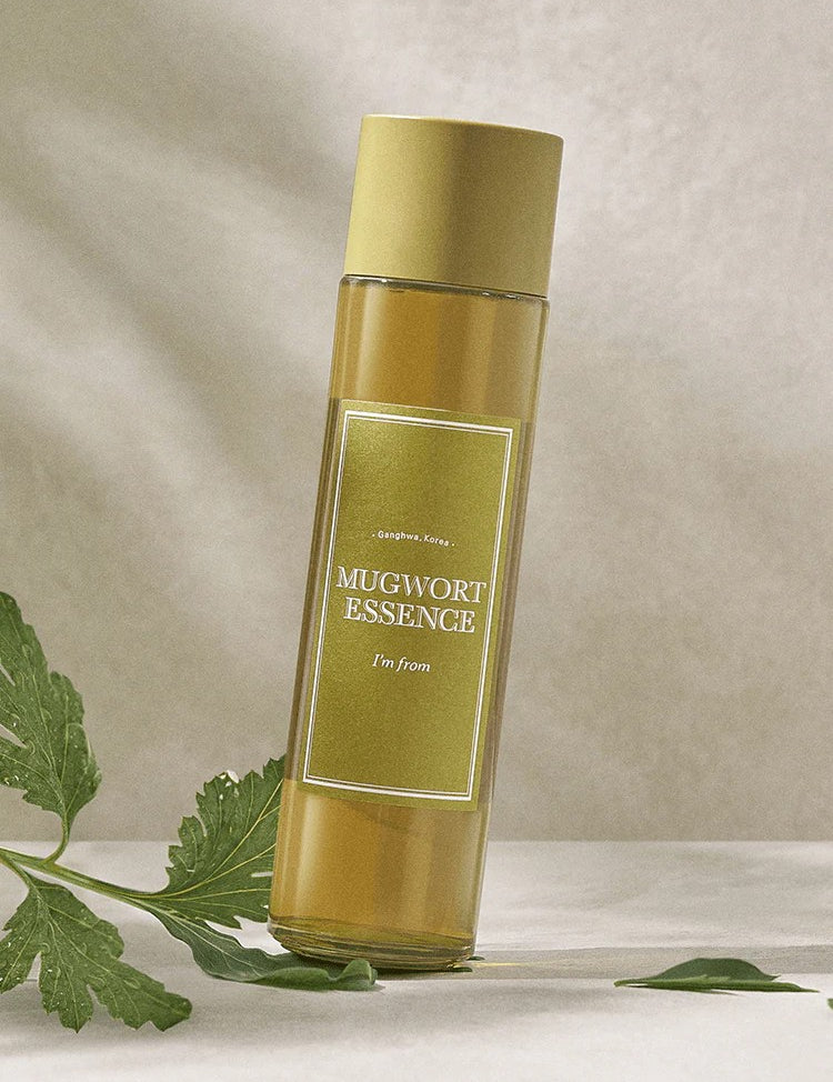 A bottle of 'I'm From' Mugwort Essence set against a soft background, with green Mugwort leaves nearby.