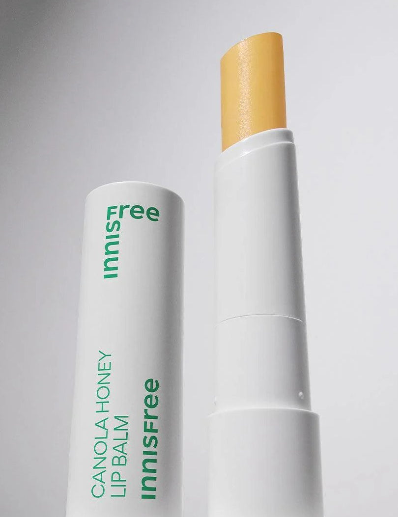Innisfree Canola Honey Lip Balm with a visible yellow stick, housed in a white container with green lettering, set against a light background.