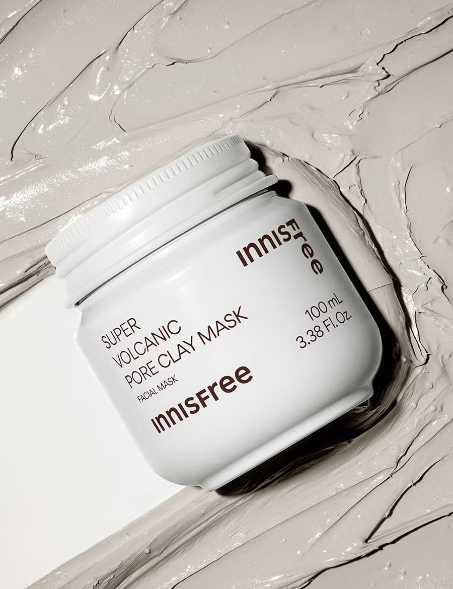 A white jar of Innisfree Super Volcanic Pore Clay Mask with its gray clay texture smeared on a clean surface.