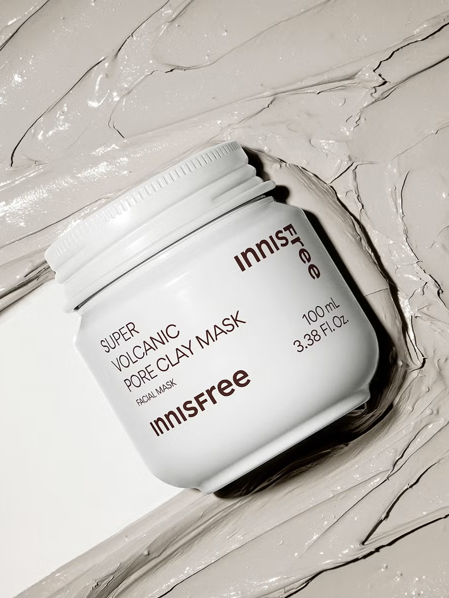 A white jar of Innisfree Super Volcanic Pore Clay Mask with its gray clay texture smeared on a clean surface.
