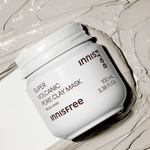 A white jar of Innisfree Super Volcanic Pore Clay Mask with its gray clay texture smeared on a clean surface.