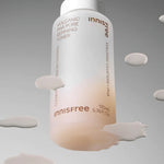 A bottle of Innisfree Volcanic PHA Pore Refining Toner with a white cap, surrounded by its lightweight texture drips against a gradient gray background, emphasizing its refining and sebum-controlling properties.