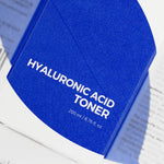 Close-up of the Isntree Hyaluronic Acid Toner's blue packaging, labeled with 200 ml / 6.76 fl. oz., on a white background.