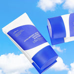 Two tubes of Isntree Hyaluronic Acid Watery Sun Gel against a bright blue sky with clouds, highlighting their vibrant packaging.