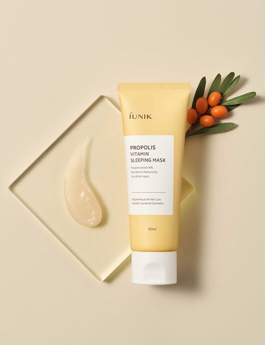A tube of iUNIK Propolis Vitamin Sleeping Mask beside a dollop of gel, with sea buckthorn berries and leaves in the background, highlighting its nourishing ingredients.