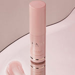 A pink Kahi Wrinkle Bounce Multi Balm bottle reflecting on a smooth surface, accompanied by a creamy swatch of the balm.
