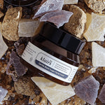Klairs Gentle Black Sugar Facial Polish in a sleek jar surrounded by natural textured stones and sugar crystals on a rustic surface, highlighting its exfoliating properties.