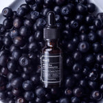 Klairs Midnight Blue Youth Activating Drop bottle placed on a bed of fresh blueberries, highlighting its antioxidant-rich formula and natural ingredients.