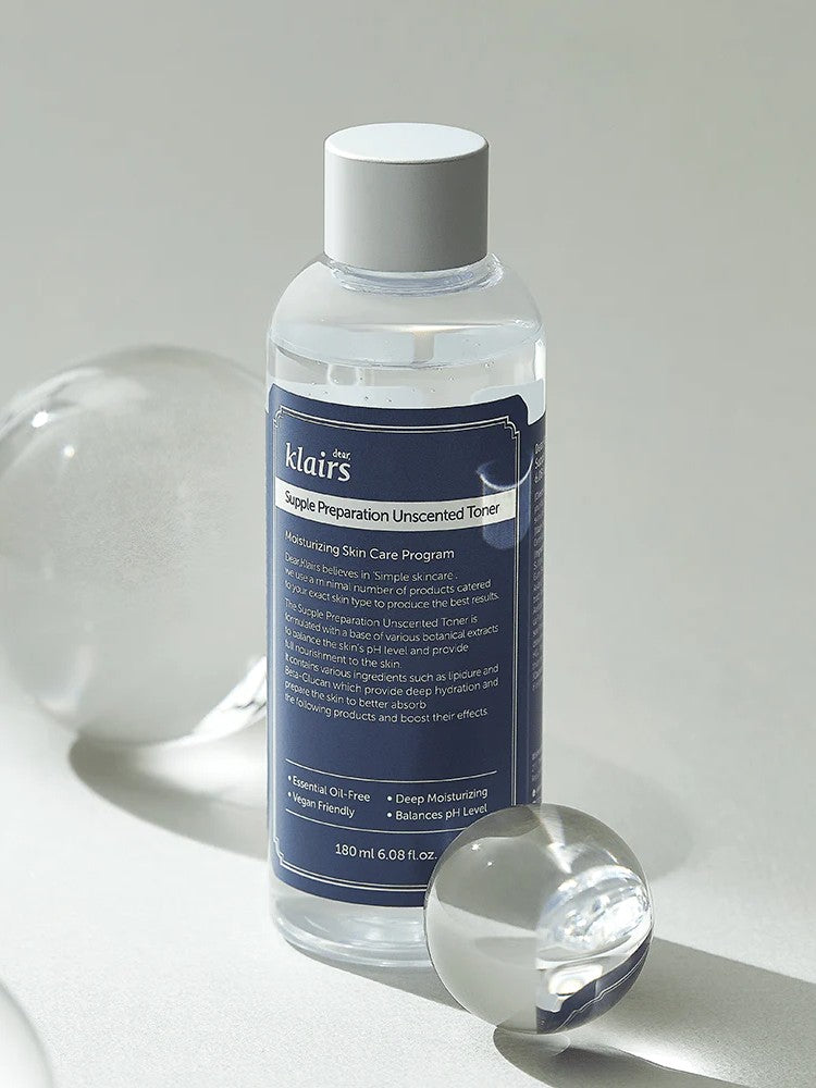Klairs Supple Preparation Unscented Toner in a clear bottle with a blue label, elegantly placed next to a round glass orb on a light background, highlighting its minimalist design and hydrating formula.