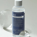 Klairs Supple Preparation Unscented Toner in a clear bottle with a blue label, elegantly placed next to a round glass orb on a light background, highlighting its minimalist design and hydrating formula.