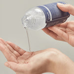 A person pouring Klairs Supple Preparation Unscented Toner into the palm of one hand, highlighting its clear, lightweight texture against a neutral background.