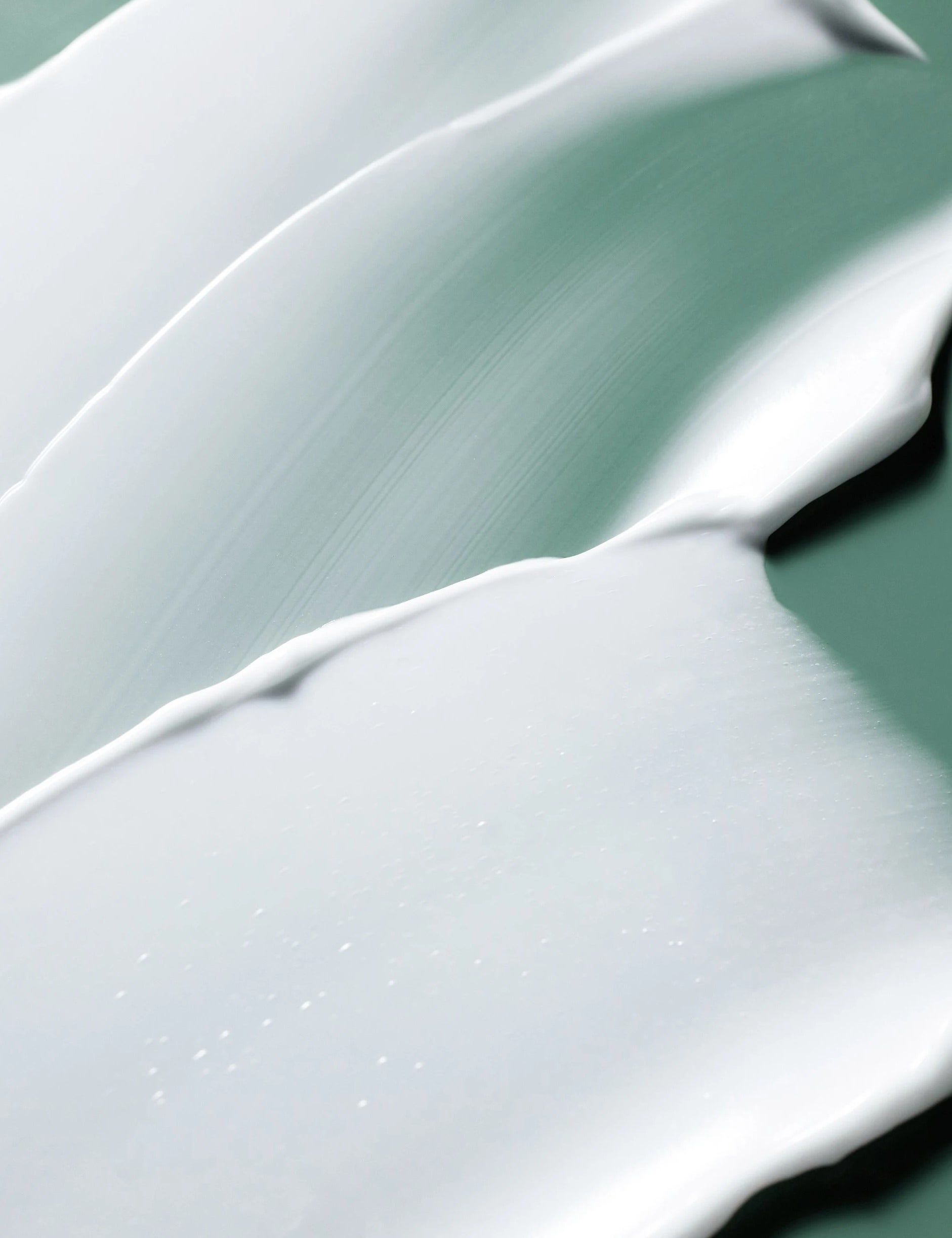 Close-up of smooth, creamy white samples of the Laneige Cica Sleeping Mask on a soft green backdrop.