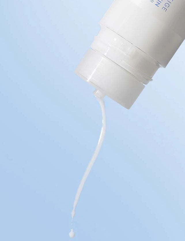 Close-up of Laneige Cream Skin Cerapeptide™ Refiner pouring its milky, lightweight liquid against a soft blue background.