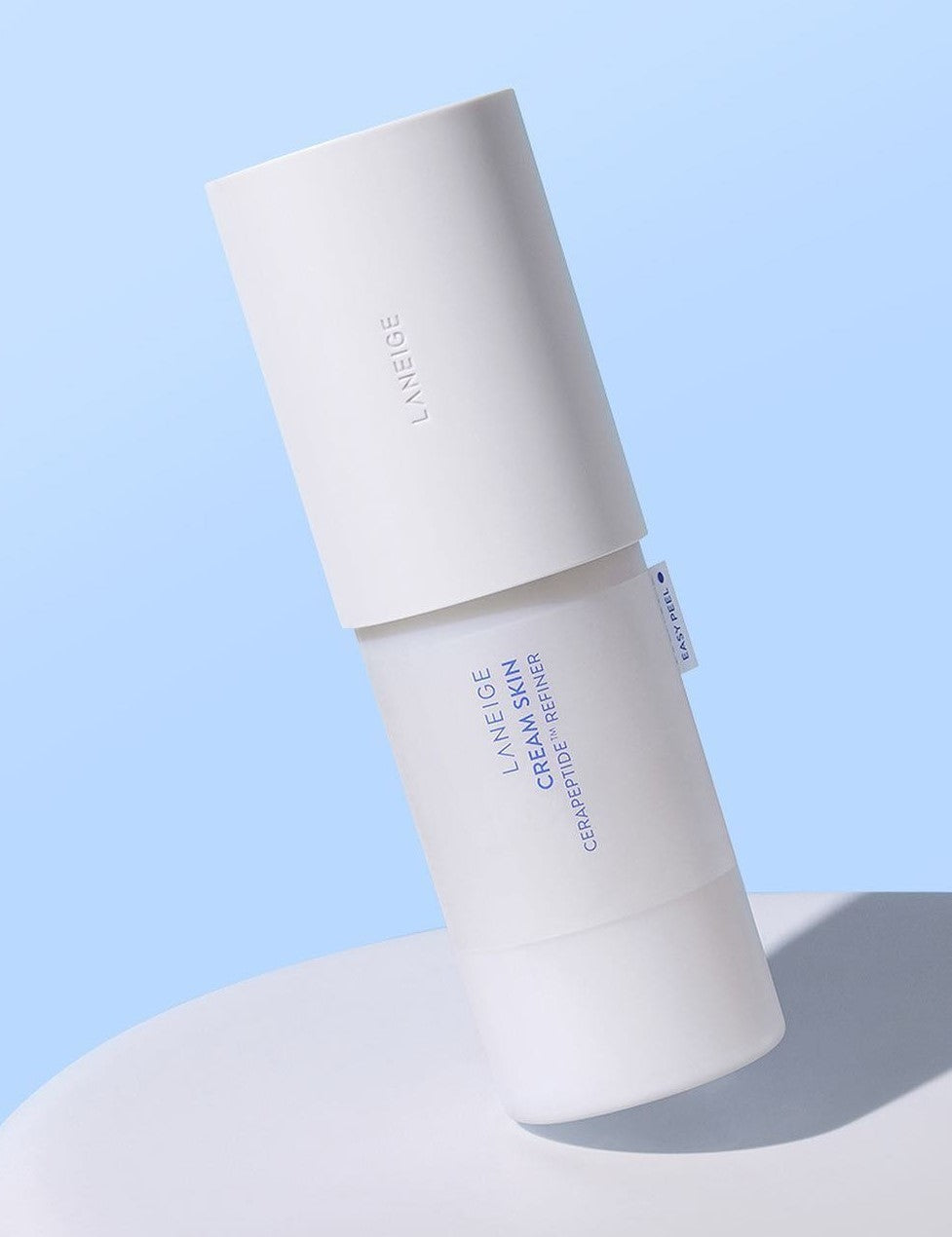 Laneige Cream Skin Cerapeptide™ Refiner resting on a smooth surface against a soft blue backdrop.