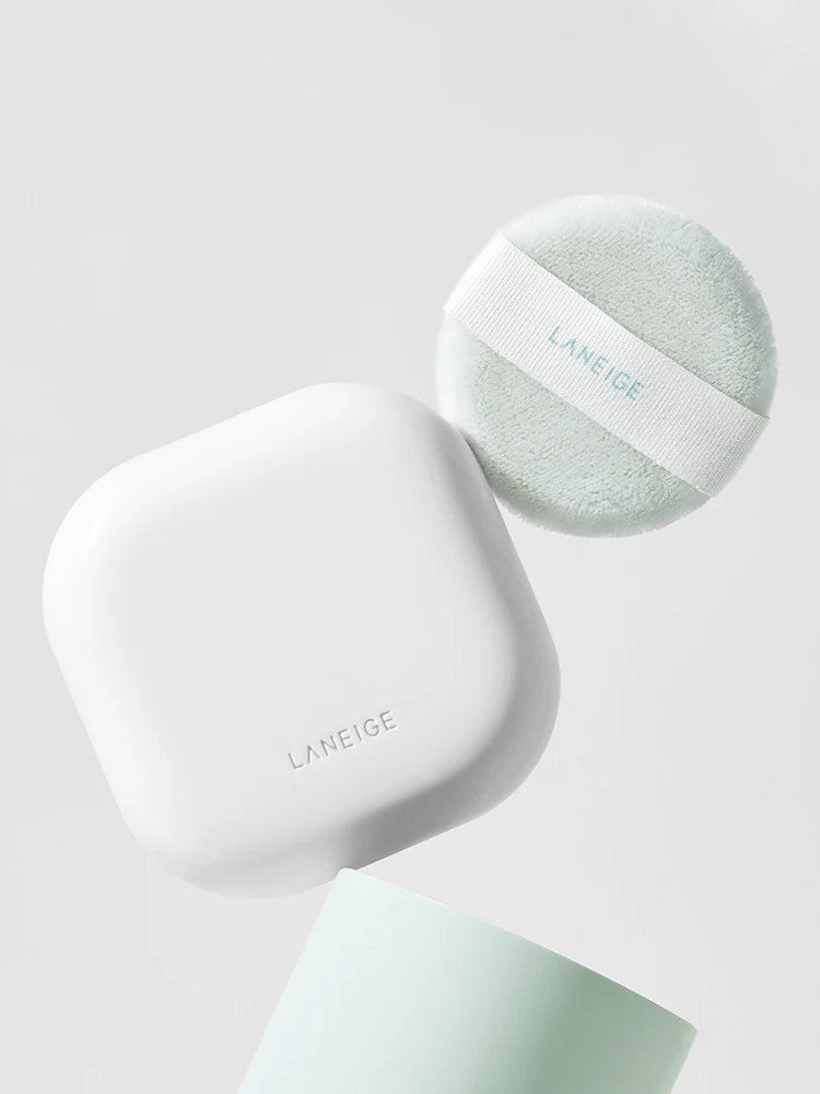 A white, square compact and mint green puff from Laneige Neo Essential Blurring Finish Powder displayed against a soft gray background.