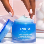 A hand reaching for the open blue jar of Laneige Water Sleeping Mask, with cotton balls and a soft towel in the background, highlighting its lightweight gel texture.