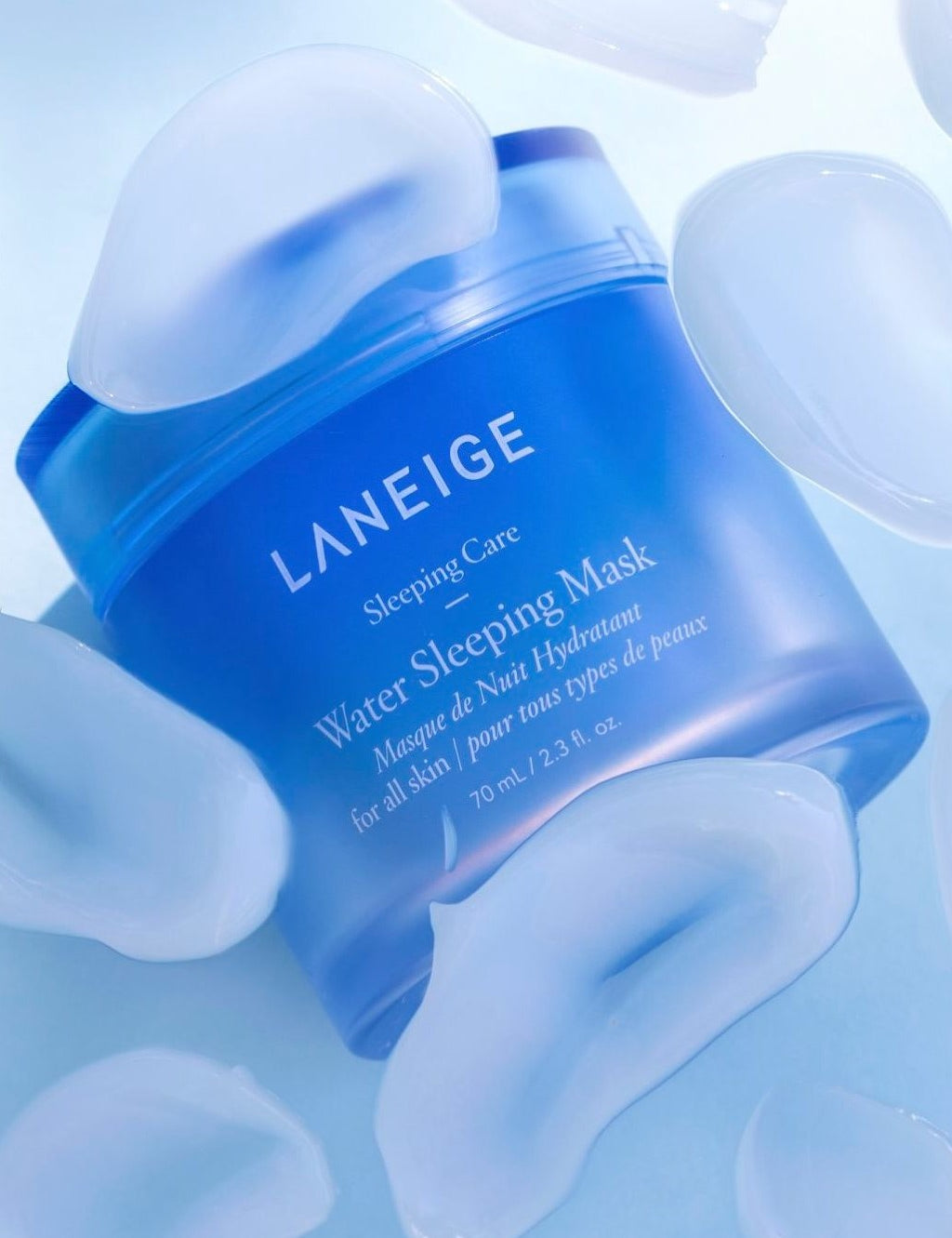 A blue jar of Laneige Water Sleeping Mask on a light background, surrounded by translucent gel droplets, highlighting its hydration and refreshing effect.