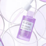 Close-up of Neogen's Real Bakuchiol Firming Serum in a purple bottle, artistically surrounded by circular translucent discs, emphasizing its innovative and firming formula.