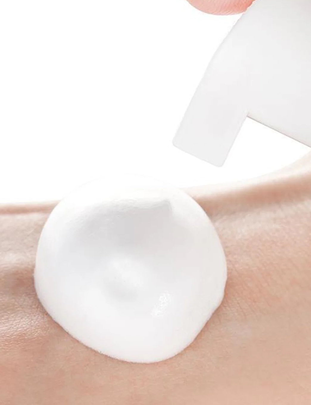 A hand holding a bottle dispenses a smooth, white foam onto the wrist, showcasing the Neogen Real Fresh Foam Blueberry Cleanser's gentle and antioxidant-rich formula.
