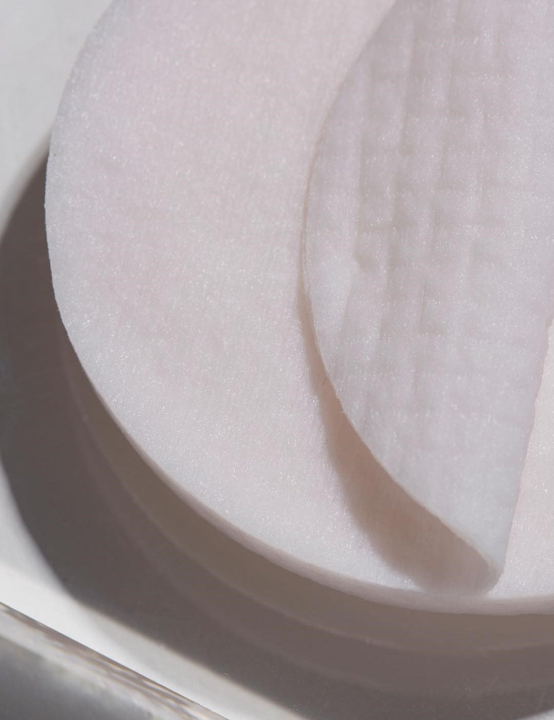 Close-up of white cotton rounds stacked together, highlighting the 100% natural viscose fabric texture of Papa Recipe Eggplant Clearing Peeling Pads.
