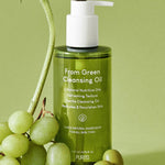 Green bottle of Purito From Green Cleansing Oil surrounded by fresh green grapes, highlighting its natural ingredients and nourishing skincare benefits.