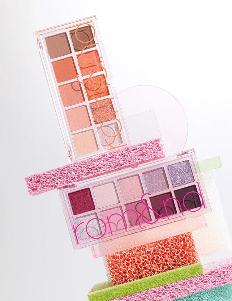 Two Romand Better Than Palette Energetic Series eyeshadow palettes stacked on vibrant sponges, showcasing shades from warm neutrals to rich purples.