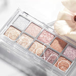 Eyeshadow palette Romand Better Than Palette Light and Glitter Garden, featuring ten shimmering shades from silver to pink and rose gold, styled with a delicate flower.