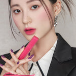 A model wearing Romand Blur Fudge Tint in the shade Bibi Candy, showcasing the soft matte texture on her lips.