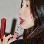 A model wearing Romand Blur Fudge Tint in the shade Currant Jam, showcasing the soft matte texture on her lips.