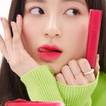 A model wearing Romand Blur Fudge Tint in the shade Fuchsia Vibe, showcasing the soft matte texture on her lips.