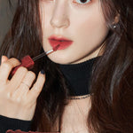 A model wearing Romand Blur Fudge Tint in the shade Musky, showcasing the soft matte texture on her lips.