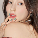 A model wearing Romand Blur Fudge Tint in the shade Pomeloco, showcasing the soft matte texture on her lips.
