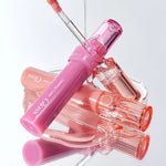 A collection of Romand Glasting Color Gloss tubes displayed elegantly, featuring a pink-tinted flexible applicator and light-reflecting shine.