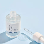 Round Lab 1025 Dokdo Ampoule with dropper and droplet, set against a light blue background.