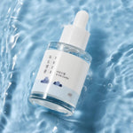 Round Lab 1025 Dokdo Ampoule resting on water, featuring a minimalist mountain-themed design.