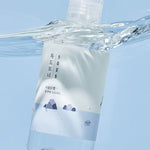 Round Lab 1025 Dokdo Toner submerged in water, featuring a minimalist design with blue and white hues and mountain graphics.
