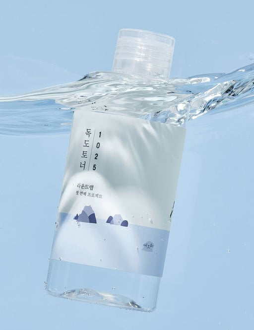 Round Lab 1025 Dokdo Toner submerged in water, featuring a minimalist design with blue and white hues and mountain graphics.