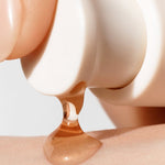 A droplet of Sulwhasoo First Care Activating Serum VI being dispensed onto a person’s skin, highlighting its smooth texture.