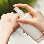 A hand dispenses a golden drop of Sulwhasoo First Care Activating Serum VI onto another hand, set against a blurred green background.