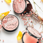 Too Cool for School Artclass By Rodin Blush in De Peche shade, surrounded by soft flowers and petals, with a makeup brush for effortless peach-toned application.
