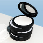 A stack of four Too Cool for School Artclass By Rodin Finish Setting Pact cases, with one case open to reveal the smooth white powder inside, displayed against a soft blue background.