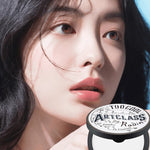 A model showcasing smooth, oil-free skin after applying Too Cool for School Artclass By Rodin Finish Setting Pact, with the product's elegant packaging details visible against a softly blurred background.