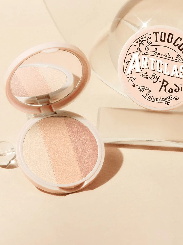 Too Cool for School Artclass By Rodin Highlighter #1 Glam, with three shimmering shades, sits open beside its decorative packaging, showcasing a pink and beige color palette.