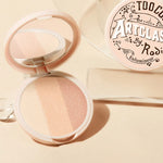 Too Cool for School Artclass By Rodin Highlighter #1 Glam, with three shimmering shades, sits open beside its decorative packaging, showcasing a pink and beige color palette.