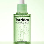 Green glass dropper bottle of Torriden's Balanceful Serum with visible bubbles, highlighting 'Centella Asiatica Extract' as a key ingredient on the label.