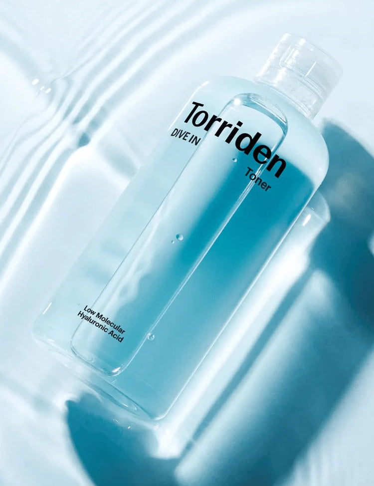 Clear toner bottle labeled 'Torriden Dive In' with 'Low Molecular Hyaluronic Acid,' sitting on wavy blue water background.