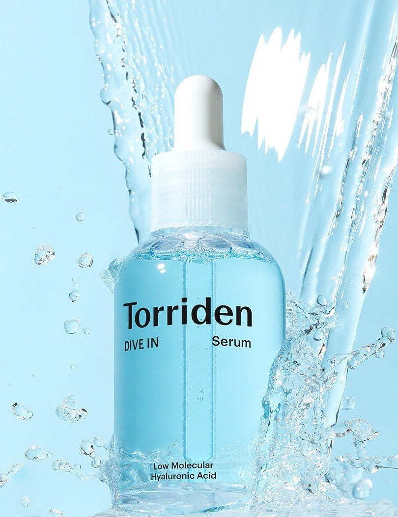 Clear bottle of Torriden Dive In Serum featuring low molecular Hyaluronic Acid, surrounded by water splashes against a blue background.