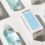 Two Torriden Dive In serum bottles with light blue liquid alongside their boxes featuring black text, emphasizing an instant boost of hydration.
